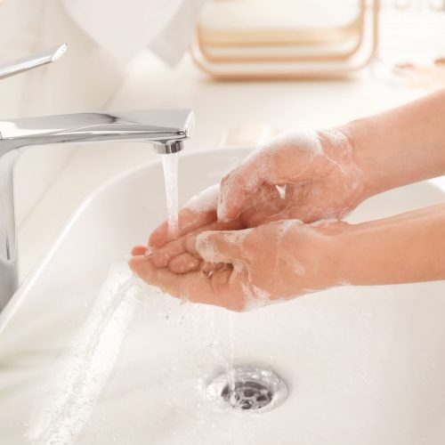 Washing soapy hands in a basin under running water