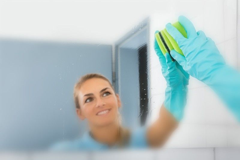 Woman cleaning a misted bathroom mirror with pad