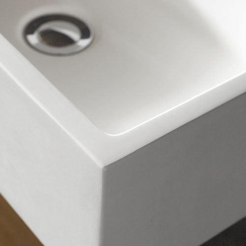The corner of a stone resin sink with a stainless steel waste plug in the background.