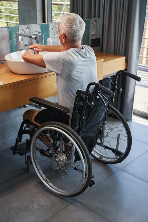 Man in a wheelchair using a wash basin